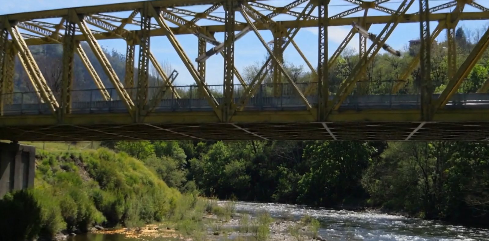 Puente de hierro sobre un río entre montes